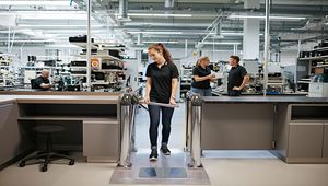 Mitarbeiterin der FSM AG in der Produktionshalle, umgeben von Arbeitsstationen und technischer Ausrüstung.